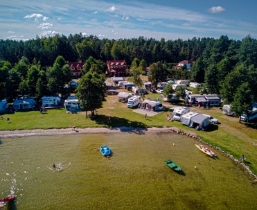 Letnia plaża na Mazurach - Tętniąca życiem plaża w Rydzewie, popularne miejsce wypoczynku nad jeziorem Niegocin w letnie dni.