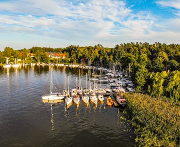 Port w Wierzbie obok jez. Śniardwy w promieniach słońca - Żaglówki i łodzie zacumowane w porcie w słoneczny dzień, malownicze miejsce na wodne przygody w sercu Mazur.