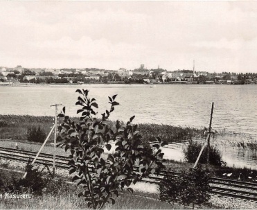 1938, Giżycko znad jeziora Niegocin - Widok na Giżycko z 1938 roku, pokazujący miasto położone nad brzegiem jeziora Niegocin, harmonijnie wpisane w mazurski krajobraz.