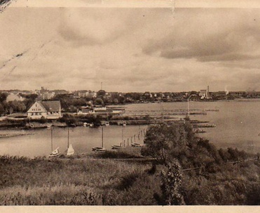 1929, Przystań żeglarska w Giżycku - Fotografia z 1929 roku przedstawia przystań z łodziami, podkreślając znaczenie Giżycka jako centrum żeglarskiego na Mazurach.